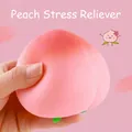 Jouet antistress en forme de pêche rose souple pressé par une main sur fond rose - Taille 7cm / Rose