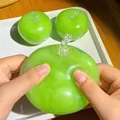 Primo piano di mani che schiacciano un realistico giocattolo antistress a mela verde - Stile Mela Verde / 1 Pezzo/Confezione / Ciano
