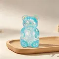 Detailed macro view of a translucent blue glittery aurora bear squishy toy on a wooden tray - Glitter Maltose Bear (Ice Blue)