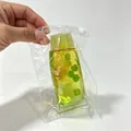 Détail d'un jouet anti-stress vert en forme de dentifrice avec trèfles dans son sachet - Style Trèfle Vert