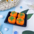 Détail de quatre squishies en forme de kaki orange sur un plateau noir pour le stress. - Lot de 4 / Kaki