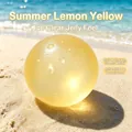 Durchscheinender zitronengelber Squishy-Stressabbau-Ball auf sonnigem Strandsand - Eistransluzente Handgemachte Kugel / Zitronengelb