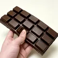 Gros plan d'un jouet squishy en forme de chocolat montrant sa texture réaliste - Bloc de chocolat / 1 Pièce / Chocolat