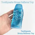 Detailed view of blue glitter toothpaste squishy toy being squeezed by hand - Blue Star Toothpaste