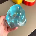 Close-up of a translucent blue squishy stress relief toy being squeezed by hand. - Ocean Blue (Transparent) / 6cm