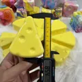 Close-up view of a simulation cheese squishy toy being measured with a digital caliper - Triangle Cheese Style / 7cm Size / Yellow
