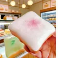 Close-up showing the soft slow rising texture of a toast squishy toy with pink topping - White Toast