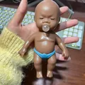 Niedliche dunkelhäutige Baby-Puppe zum Drücken mit blauer Windel zum Stressabbau - Blasen Spuckender Stil