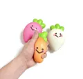 Detail showing a hand squeezing a soft cartoon vegetable slow rebound stress relief toy. - Carrot