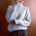 Close-up detail of a light blue high turtleneck sweater with a diamond knit pattern. - Light Gray