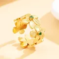 Eleganter vergoldeter Edelstahlring mit Blumenmuster und funkelnden grünen Steinen - Grüne Straßblume (J03329B) / Gold