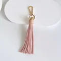 Detail view of a pink leather tassel bag charm with a glossy gold-colored metal clasp - Tassel Style / 10cm / Nude