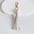 Detailed macro view of 10cm white leather tassel keychain with polished gold lobster clasp - Tassel Style / 10cm / Marble Gray