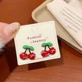 Cute cherry red stud earrings with green leaf detail presented on a jewelry card - New Year Red Cherry (YTW2)
