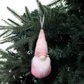 Handgemaakte roze gebreide kerstkabouter ornament aan een groene dennenboom tak - Roze en Wit