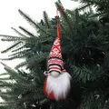 Décoration de gnome de Noël tricoté rouge et blanc suspendue à un sapin vert foncé - Combinaison de couleurs noir, blanc, rouge