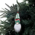 Gnome de Noël tricoté à la main suspendu à une branche de sapin vert foncé - Rouge et Vert Classique