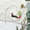 Runder Weihnachts-Dachshund-Anhänger mit weißem Band auf gemütlichem Strickstoff - Weihnachts-Dackel-Stil (07)