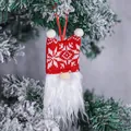 Handmade red knitted Christmas gnome ornament with white beard on a frosted tree - Snowflake Style
