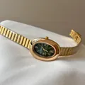Detalle de reloj vintage dorado para mujer con esfera ovalada verde y correa flexible - Correa Dorada Esfera Verde