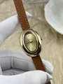 Primer plano de reloj de mujer ovalado dorado con correa de cuero marrón y números romanos. - Caja Dorada Correa de Cuero Marrón (75011)