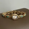 Détail d'une montre bracelet dorée de style vintage avec d'élégantes pierres vertes - Vert Turquoise Avec Cadran Blanc Et Cadre Doré