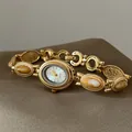 Vue détaillée d'une montre-bracelet dorée vintage avec incrustations de pierres sur tissu - Jaune Avec Cadran Blanc Et Cadre Doré