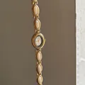 Vue détaillée d'une montre bracelet vintage dorée avec d'élégants maillons crème - Blanc Cassé Avec Cadran Blanc Et Cadre Doré
