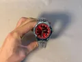 Elegant silver Y2K wormhole concept watch with a red dial held by a male hand - Silver Red