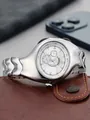 Professional shot of silver Y2K aesthetic irregular distorted quartz wristwatch on leather wallet - Matte White