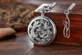 Gros plan d'une montre de poche mécanique vintage en argent avec gravure de dragon - Dragon Argent Manuel