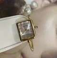 Detaillierte Nahaufnahme einer goldenen quadratischen Armreif-Uhr mit Perlenakzenten - Quadratischer Perlenstil / Goldenes Stahlarmband Weißes Zifferblatt