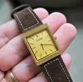 Gros plan sur la montre carrée vintage CILOA avec boîtier doré et bracelet en daim marron - Style Cadran Échelle Bracelet Brun (544) / Bracelet Brun Cadran Or Échelle