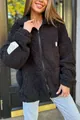 Detail van zwart sherpa fleece vest met witte label patches - S / Tops / Zwart