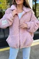 Detailopname van een knus roze sherpa fleece vest met een decoratieve mouwpatch - S / Tops / Roze