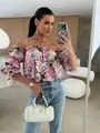 Detailed view of a floral off-shoulder puff sleeve blouse styled with light blue jeans. - S / Tops / Purple Flower