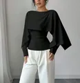 Vista detallada de un top negro estilo capa con cuello redondo y diseño elegante. - Negro