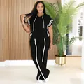 Model wearing a black hooded two-piece set with white side stripes and wide-leg pants - S / Top And Bottom / Black