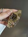 Detalle de un reloj vintage dorado para mujer con números romanos en esfera negra - Dorado Negro