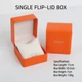 Detalle de una caja de reloj naranja con tapa y cojín blanco - Caja Naranja