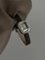 Nahaufnahme der GUOU Vintage Quarzuhr für Damen mit einem schwarzen Lederarmband - Vintage Ovaler Stil (8271) / Graues Armband Graues Silbergehäuse