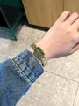 Close-up detail of an elegant IBSO gold-toned rectangular watch styled on a female wrist - Gold Green