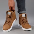 Macro detail view of brown high-top casual fashion boots featuring white rubber soles - Tan
