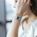 Elegant silver square quartz watch with crystal bezel and mesh band on woman's wrist - Silver Black