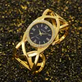 Close-up of a vintage gold bangle watch featuring a rhinestone bezel and crossover strap - Gold Black