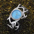 Close-up of a silver cuff watch with a light blue dial and rhinestone-set bezel. - Silver & Blue