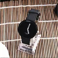 Dettaglio dell'orologio di moda WOMAGE con quadrante nero e cinturino intrecciato - Nero