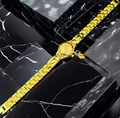 Primo piano di un lussuoso orologio bracciale da donna dorato con ciondolo a cuore. - Oro-Numeri Completi