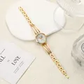 Detailed view of an elegant women's gold quartz watch with rhinestone accents on white stone - Gold