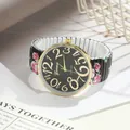Close-up of ladies' rose print quartz watch with large golden numbers and elastic band. - Black